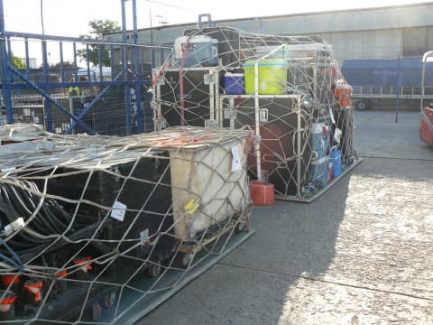 Touring equipment secured on air freight pallets with cargo nets at an airport freight terminal
