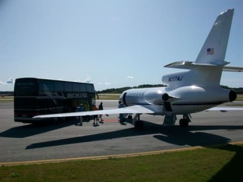Beat The Street tour bus alongside private jet on airport apron during touring production