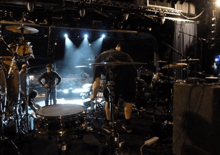 Drum kit backline setup during soundcheck at Swiss venue with stage lighting and production crew