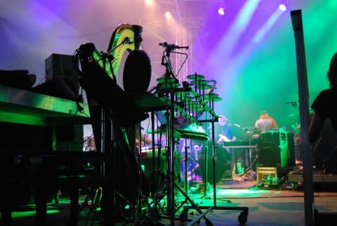 Stage lighting rig with green and purple wash illuminating a live outdoor concert stage