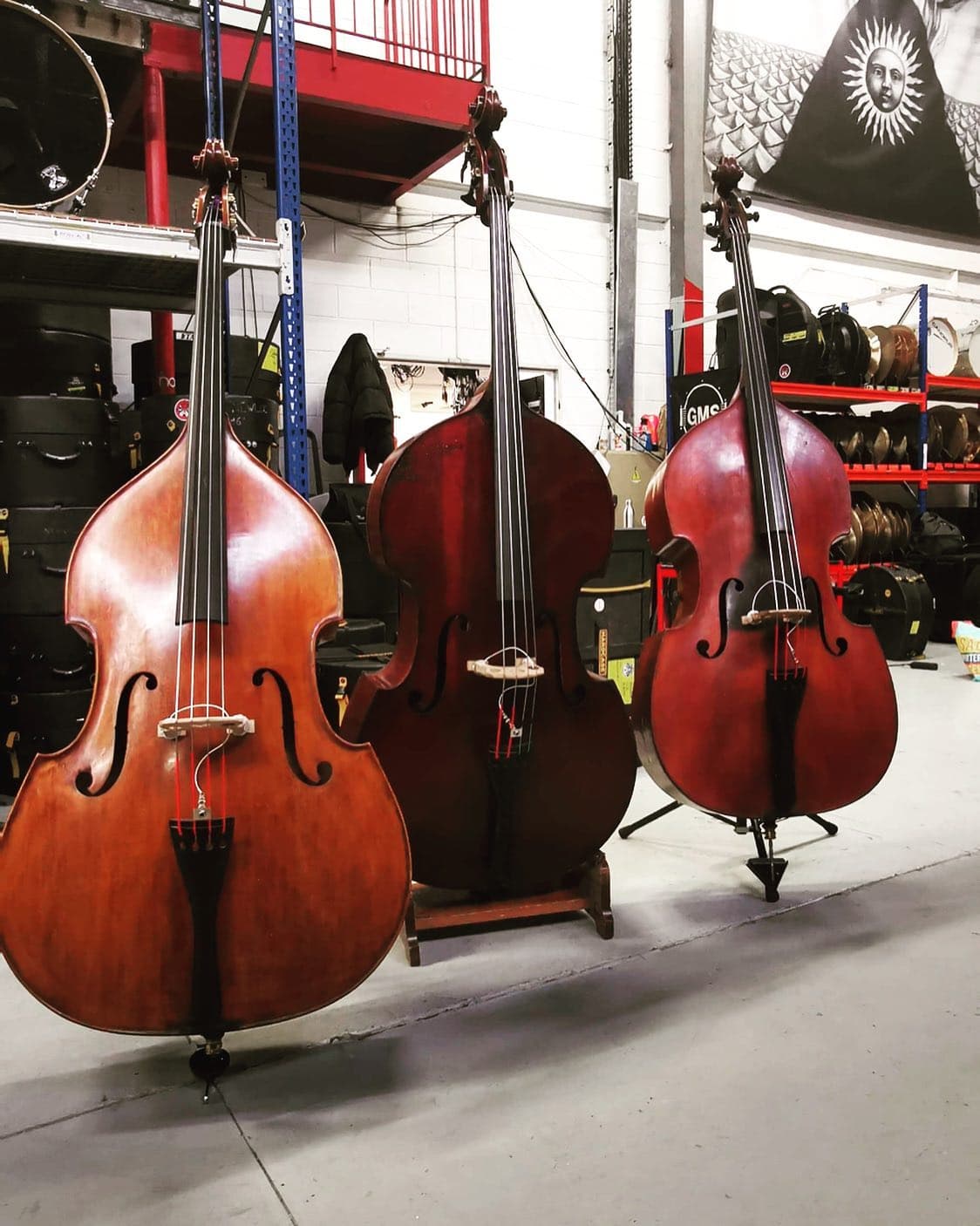 Double bass instruments in Newloc Paris backline hire warehouse with drum flight cases and cymbal storage